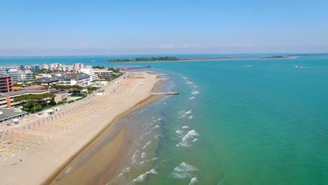 Aerial-view-of-the-wide-sandy-beach-with-sun-loungers-and-umbrellas-on-the-coast-of-the-Italian-peninsula-Lignano-Adriatic-sea