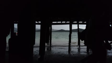 Silhouette-of-two-young-people-sneaking-under-the-docks-at-the-beach