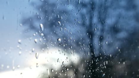 Rainy-storm-droplets,-moody-weather-fall-down-window-glass-closeup-bokeh