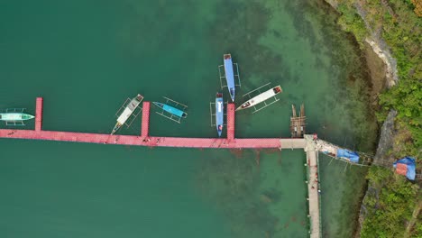 Obenliegende-Aufsteigende-Luftaufnahme-Von-Philippinischen-Banca-Booten,-Die-In-Tropischem-Aquablauem-Wasser-Neben-Einer-Insel-In-4k-Angedockt-Sind