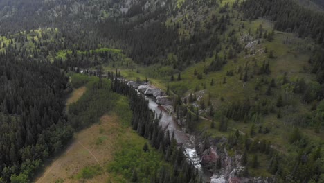 Aerial-drone-footage-of-a-river-flowing-trough-forest-and-land-in-Alberta,-Canada