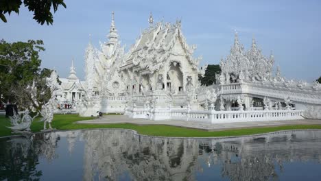 Front-movement-into-the-White-Temple-over-the-main-lake,-Chiang-Rai,-Thailand