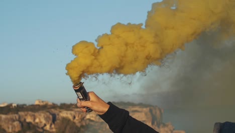 Man-holds-a-yellow-smoke-bomb-in-his-hand---Slow-Motion-Footage