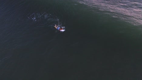 Aerial:-Surfer-paddling-over-ocean-breaking-wave