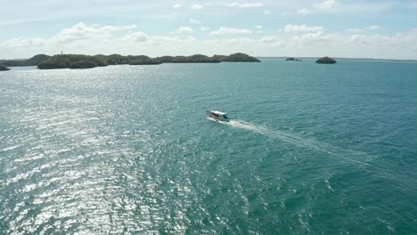 Abgewinkelte-Verfolgungsjagd-Eines-Banca-Bootes,-Das-Auf-Blauem-Wasser-In-Richtung-Inseln-4k-Segelt