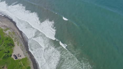 Aerial:-waves-breaking-on-Pacific-Coast,-ocean-whitewater,-tilt-follow