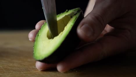 Dicing-light-green-avocado-inside-its-skin-with-tip-of-sharp-chefs-knife