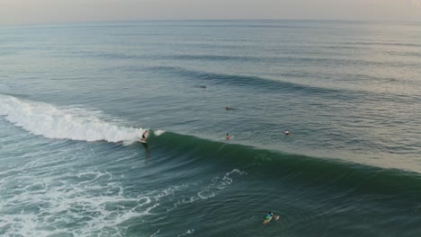 Aerial:-amazing-surfers-riding-wave-at-sunset-in-Mexico,-Pacific-Ocean