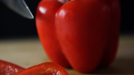 Sharp-chefs-knife-slice-through-side-of-red-bell-pepper-and-cutting-it-off