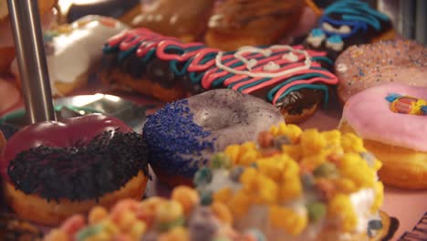4k-Nahaufnahme-In-Zeitlupe-Von-Vielen-Verschiedenen-Ungesunden-Donuts---Mit-Verschiedenen-Bunten-Und-Süßen-Belägen---Nahaufnahme---Amerikanisches-Junk-Food---Voodoo-Donuts-In-Portland