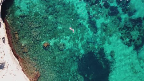 Birds-eye-view-of-people-swimming-in-crystal-clear-blue-and-turquoise-water---4k-footage