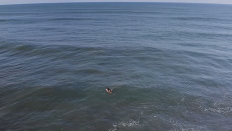 Aerial:-surfer-paddling-over-waves-in-tropical-ocean-water