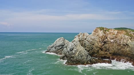 Aerial:-waves-crashing-against-rocks-on-rugged-coastal-cliffs,-arc-shot