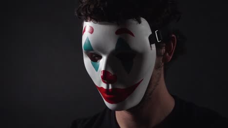 Man-Wearing-The-Joker-Themed-Clown-Mask-in-Dark-Black-Room
