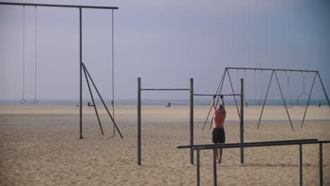 4K-Zeitlupenaufnahmen-Eines-Mannes,-Der-In-Einem-Trainingspark-An-Einem-Strand-Trainiert---Ein-Mann,-Der-Im-Freien-Klimmzüge-Macht---Muskelpark---Venice-Beach---Santa-Monica-Los-Angeles