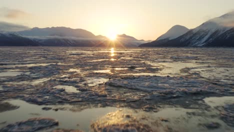 Perfect-cinematic-aerial-flying-over-ice-sheets-tilt-up-camera-revealing-sunrise