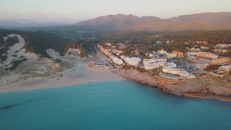 Stunning-aerial-view-of-the-coastline-in-the-north-of-Mallorca---Cala-Mesquida-with-hotels-while-sunrise---Touristic-area-Majorca