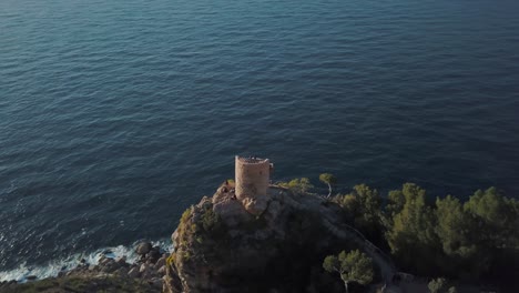 4k-orbit-aerial-shot-of-the-stone-tower-Torre-del-Verger-in-Mallorca,-Spain---Spanish-tourist-hotspot-in-Europe---Serra-de-Tramuntana-Majorca