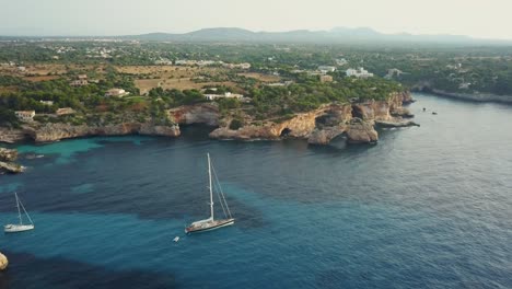 Amazing-view-of-the-east-coast-of-Mallorca,-Spain---Es-Pontas-Cala-Santanyi---Cliffs-rock-formation---Sailing-yachst-in-turquoise-water-while-sunrise