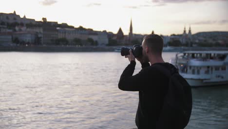 Photographer-taking-pictures-of-the-Budapest-skyline-next-to-the-Donau-river-while-sunset