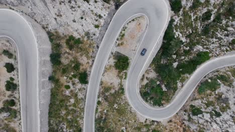 Stunning-4k-top-down-view-of-a-car-driving-through-very-curvy-serpentines---Mallorca-Sa-Calobra-Serra-de-Tramuntana---Curvy-and-dangerous-mountain-street---Driving-on-mountain-road