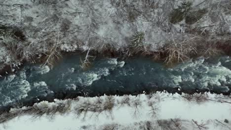 Amazing-winter-river-scene-flowing-down-snowy-mountainside,-top-down-aerial-view