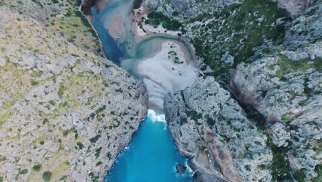 Breathtaking-4k-aerial-top-down-view-in-4k-of-the-famous-beach-Sa-Calobra-in-Mallorca,-Spain---Wide-view-Serra-de-Tramuntana---Massive-cliff-landscape-at-the-ocean---Mediterranean-Sea-Balearic-Islands