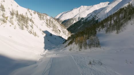 Aerial:-ski-run-through-Austrian-Alps-mountain-valley,-winter-snow