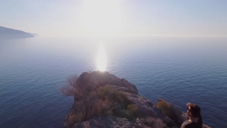 4k-drone-footage-of-man-climbing-on-cliff-and-enjoying-the-view-of-the-ocean---Enjoying-life---Traveller-makes-holiday---Mallorca-Sa-Foradada-Serra-de-Tramuntana