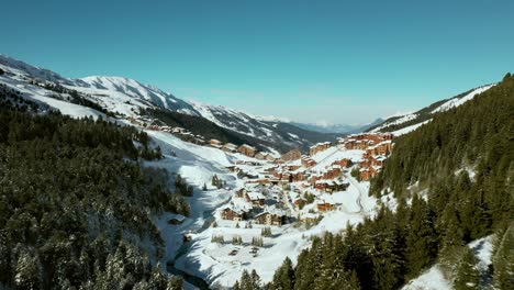 Aerial:-amazing-Val-Thorens-ski-resort-chalets-on-mountainside,-sunny-day