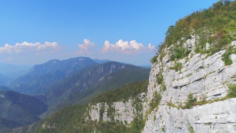 Aerial-dolly-in-alongside-a-stone-wall-in-Kostel-valley-with-mountains-in-background,-Slovenia