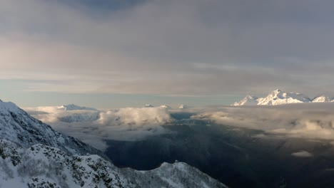 über-Den-Wolken-Luftaufnahme-Der-Schneebedeckten-Berge-Im-Winter