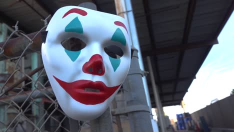 Die-Clown-Maske-Mit-Joker-Thema,-Die-An-Einem-Maschendrahtzaun-Hängt