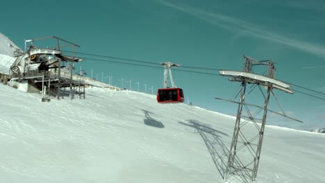 Gondola-cable-car-tram-arriving-at-top-of-mountain-lift,-aerial-view