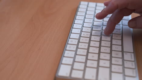 älterer-Menschlicher-Handfinger,-Der-Eine-Weiße-Tastatur-Im-Hölzernen-Schreibtisch-Schreibt