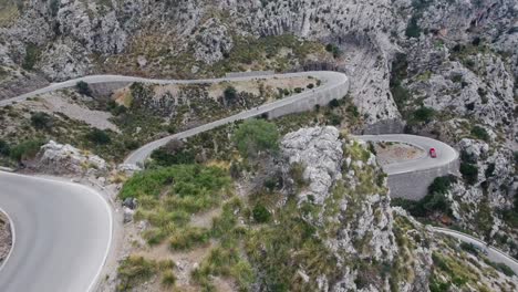 Erstaunliche-Drohne,-Die-Eine-Aufnahme-In-4k-Von-Verrückten-Serpentinen-Auf-Mallorca-Mit-Durchfahrenden-Autos-Und-Zwei-Personen-Beim-Downhill-skating-Aufdeckt---Kurvenreiche-Straßen-Auf-Mallorca---Serra-De-Tramuntana---Spanien-Balearen