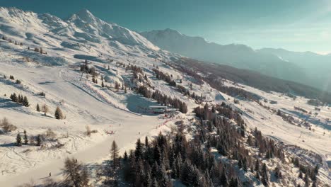 Beautiful-ski-resort-slopes-on-snowy-mountainside,-sunny-aerial-view