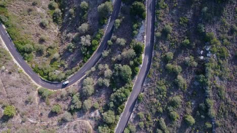 Top-down-shot-in-4k-of-car-driving-trough-serpentines-on-a-sunny-day---Dangerouse-mountain-Road-from-above