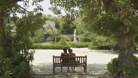 Pareja-Romántica-Sentada-En-Un-Banco-Del-Parque-Mostrando-Afecto