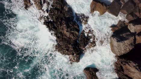 4k-top-down-view-of-rocks-in-stormy-wild-water-with-small-waves