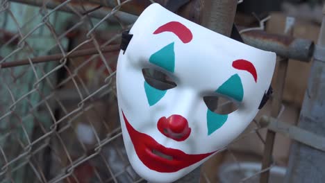 Die-Clown-Maske-Mit-Joker-Thema,-Die-An-Einem-Maschendrahtzaun-Hängt