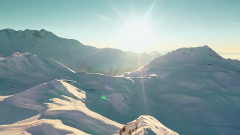 Aerial:-winter-mountain-peak-landscape,-sun-shining-above-mountain-summit