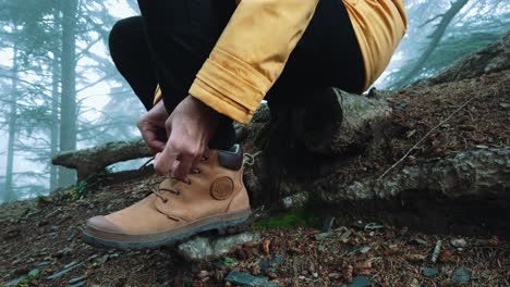 Closeup-of-man-sit-down-wearing-hiking-shoe-tying-shoelaces-inside-forest-