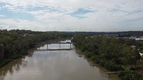 Aerial-view-of-a-brown-river-and-flying-towards-a-bridge