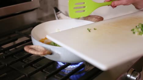 Woman-Adding-Chili-Pepper-To-Pan-Of-Cooking-Vegetables-In-Slow-Motion