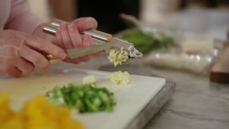 Woman-Using-Garlic-Press-Over-Cutting-Board-In-Slow-Motion