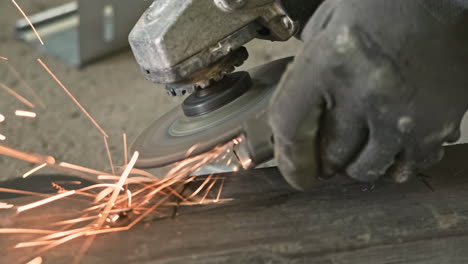 Worker's-Hand-With-Gloves-Using-An-Angle-Grinder-And-Generate-Sparks---close-up