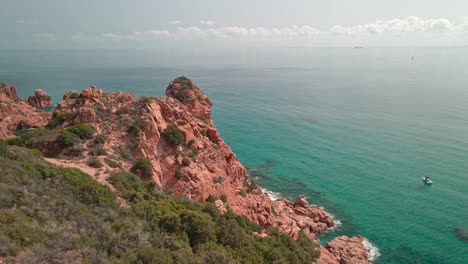 Cinematic-Drone-Flying-Over-A-Red-Cliff-With-Tropical-Cleary-Water-Sea-On-A-Beautiful-Sunny-Day-at-Sardinia,-Italy---aerial-shot