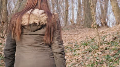 Back-View-Of-A-Long-Haired-Woman-In-Winter-Jacket-Walking-Deep-In-Forest-During-Winter-On-A-Sunny-Day