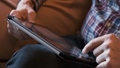 Man-scrolling-through-his-newsfeed-on-a-tablet---close-up